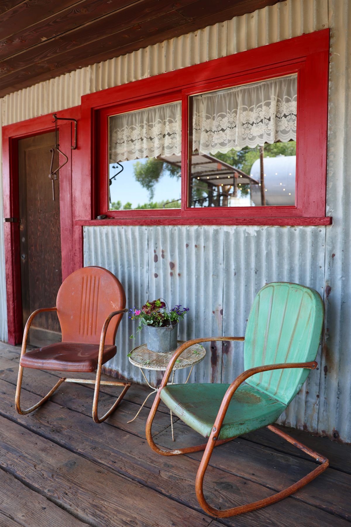 Vintage porch seating against corrugated metal and red trim.